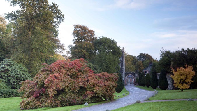 A path leading towards and arched gateway at Rowallane Garden, County Down. A variety of trees in autumn colours line the route towards the gate.